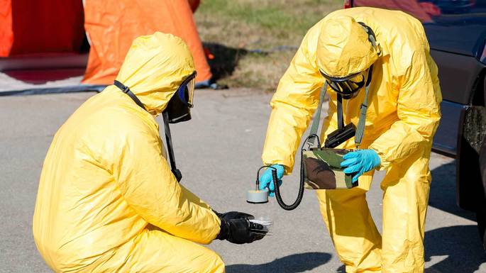 Equipo de protección midiendo la radiacion en muestras de una zona radiactiva